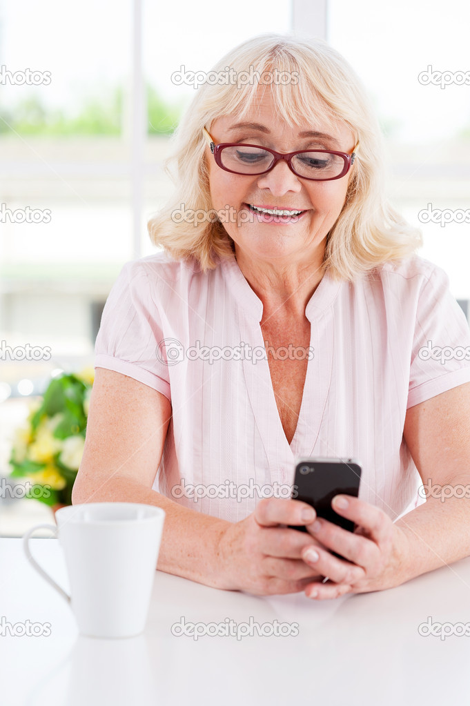 Cheerful senior woman looking at mobile phone