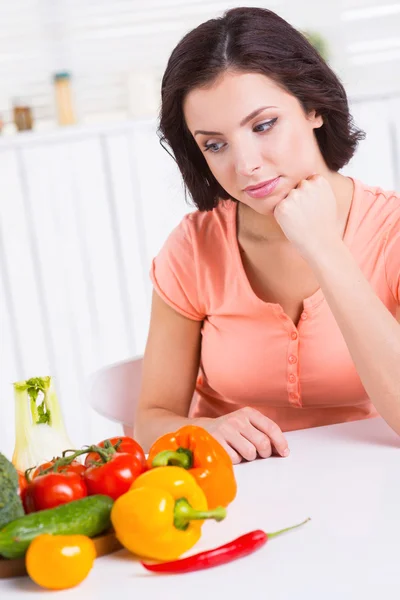 Vrouw kijken naar de groenten — Stockfoto