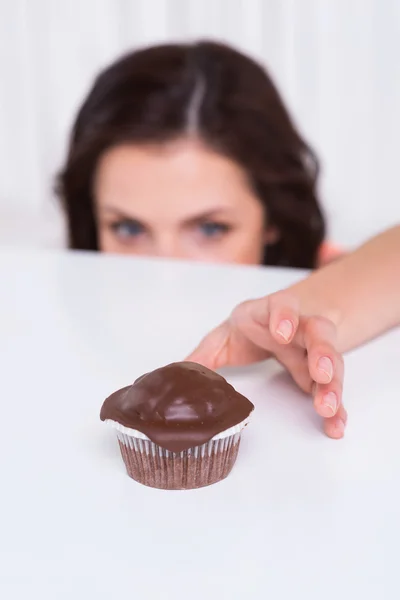 Woman stretching hand to muffin — Stock Photo, Image