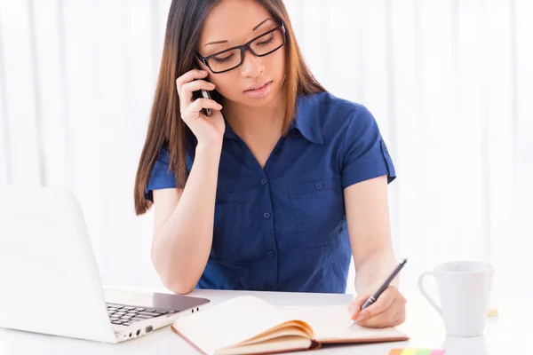 Asiatisk kvinna skriver i sitt anteckningsblock — Stockfoto