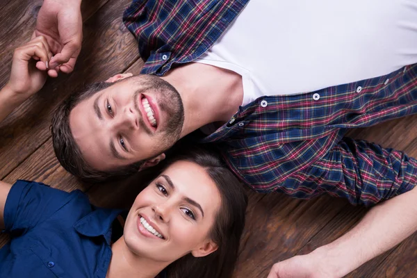 Loving couple lying on hardwood floor — Stock Photo, Image