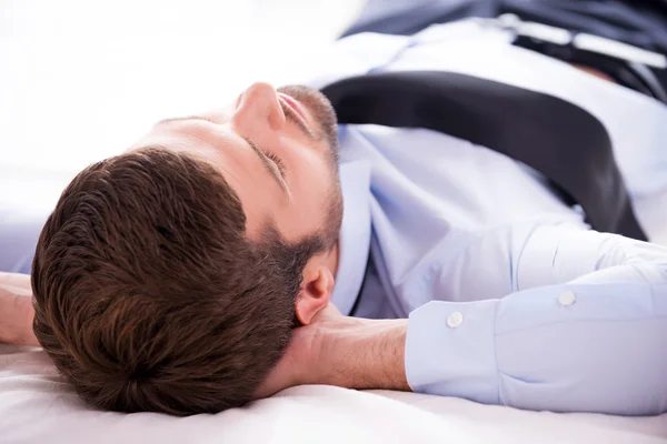 Nuori mies paidassa nukkuu sängyssä — kuvapankkivalokuva