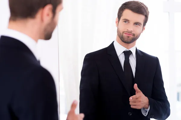 Hombre de traje de pie contra el espejo —  Fotos de Stock