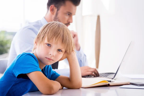 Boy holding hand in hair while  busy father working — Stock Photo, Image