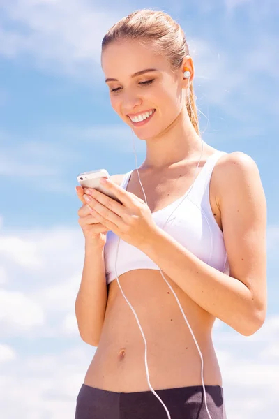 Woman in sports wear using smart phone — Stock Photo, Image