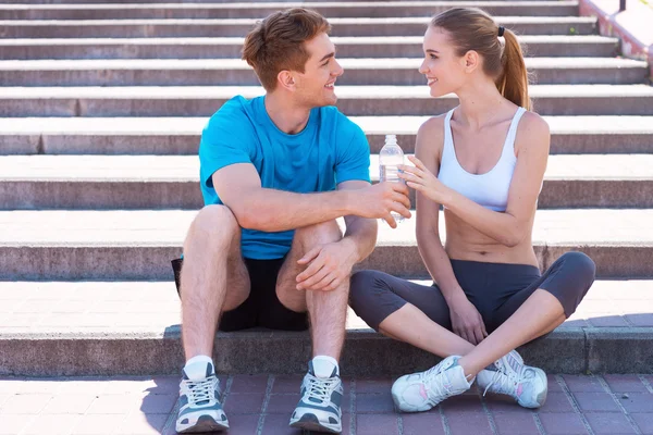 Couple in sports clothing sitting on stairs — Stock Photo, Image