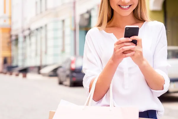 Mulher segurando sacos de compras e telefone celular — Fotografia de Stock