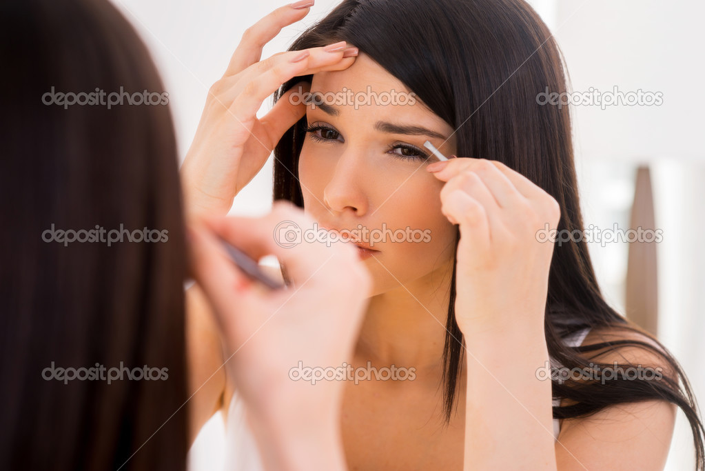 Woman tweezing eyebrows