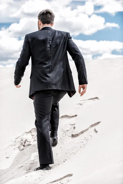Hombre en ropa formal levantándose por la duna del desierto —  Fotos de Stock