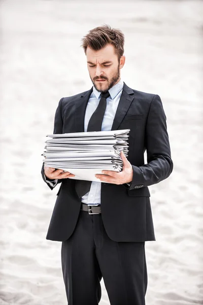 Empresario sosteniendo pila de papeleo — Foto de Stock