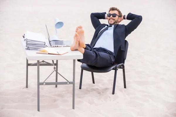 Hombre en ropa formal y gafas de sol sosteniendo sus pies en la mesa — Foto de Stock