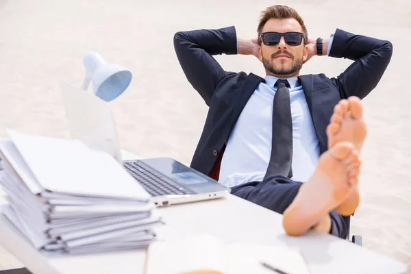 Hombre en ropa formal y gafas de sol sosteniendo sus pies en la mesa — Foto de Stock