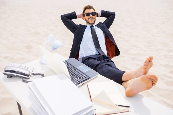 Mann in offizieller Kleidung und Sonnenbrille hält seine Füße auf dem Tisch — Stockfoto