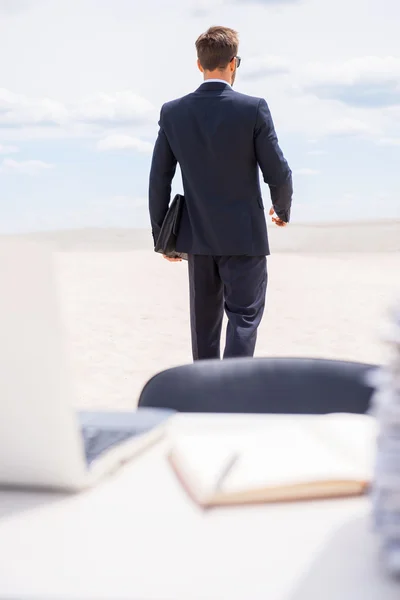 Man in formal wear walking away from working place — Stock Photo, Image