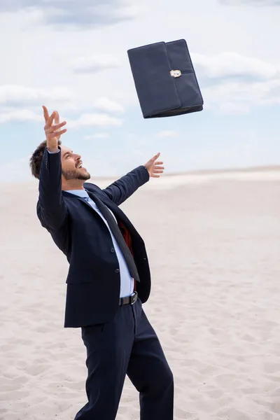 Man in formal wear throwing briefcase — Stock Photo, Image