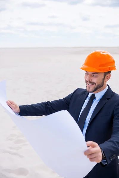 Man in formal wear and hardhat examining blueprint — Stock Photo, Image