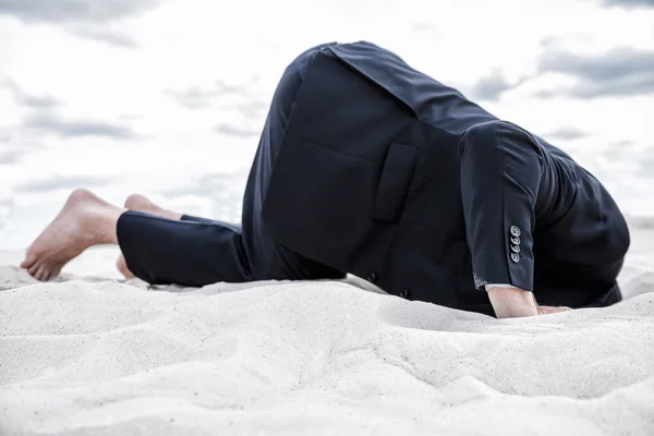 Man in formal wear hiding his head in sand — Stock Photo, Image