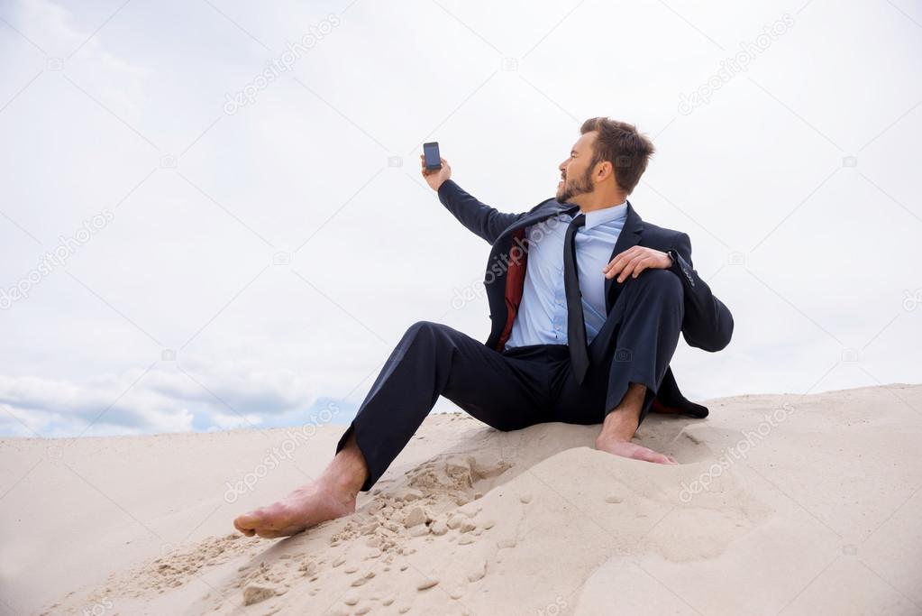 Businessman searching for mobile signal in desert