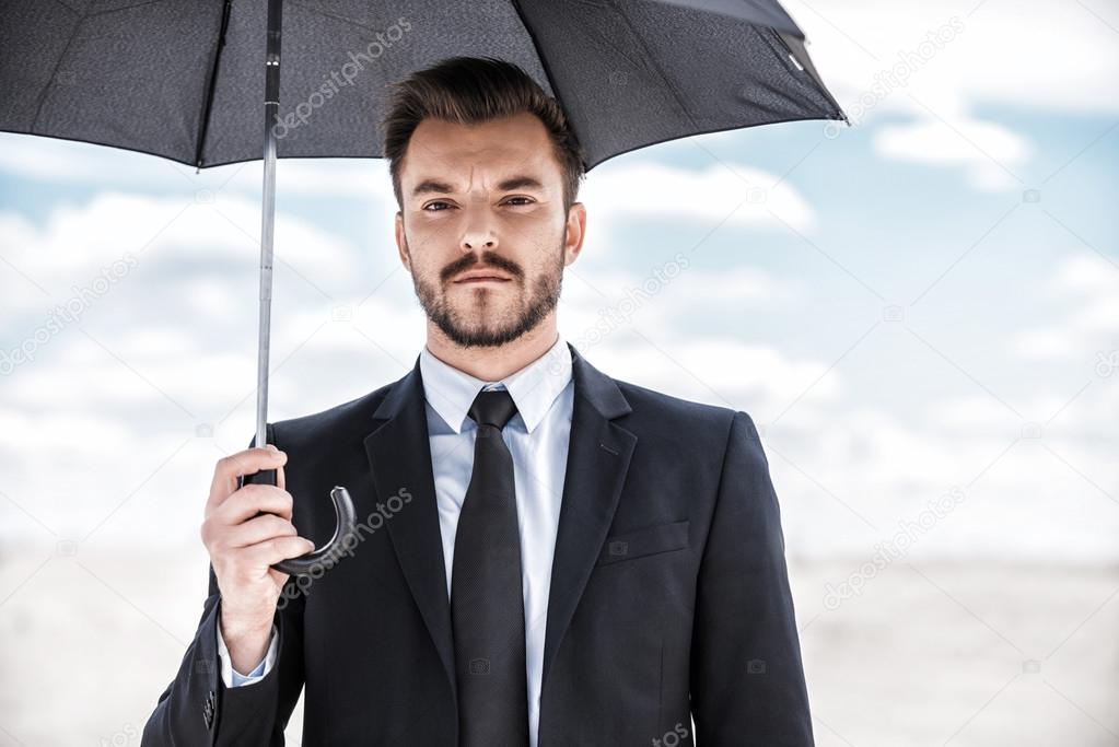 Man in formal wear holding umbrella