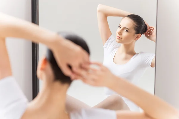 Ballerina che aggiusta i capelli contro lo specchio — Foto Stock
