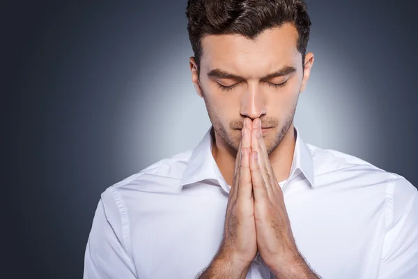 Man in white shirt holding hands clasped near face — Stock Photo, Image