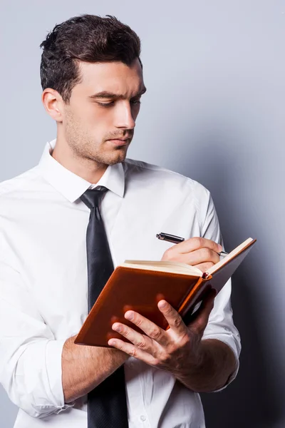 Mann in Hemd und Krawatte schreibt in Notizblock — Stockfoto