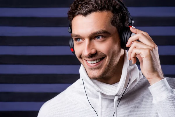 Man in white sweater adjusting his headphones