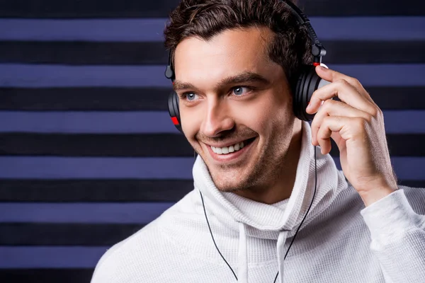 Man in white sweater adjusting his headphones — Stock Photo, Image