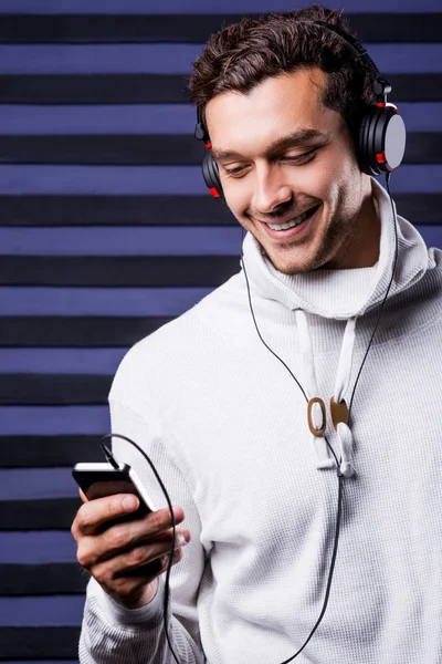 Jeune homme dans un casque tenant un lecteur MP3 — Photo