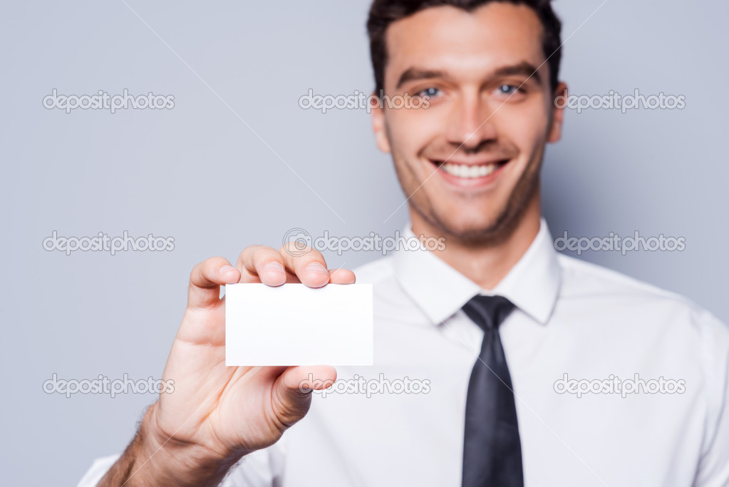 Man in shirt and tie showing his business card