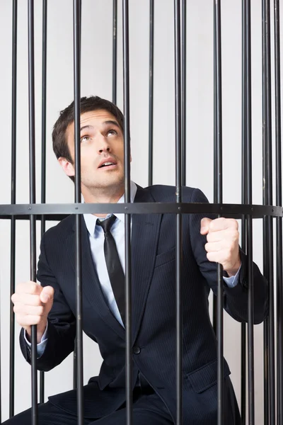 Man in formalwear standing behind a prison cell — Stock Photo, Image
