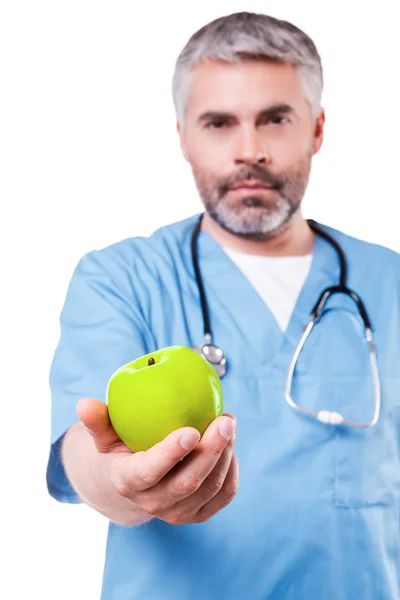 Surgeon in blue uniform stretching out apple — Stock Photo, Image