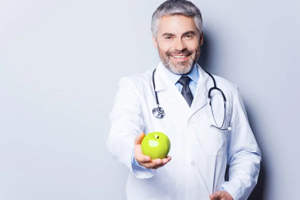 Doctor giving green apple — Stock Photo, Image