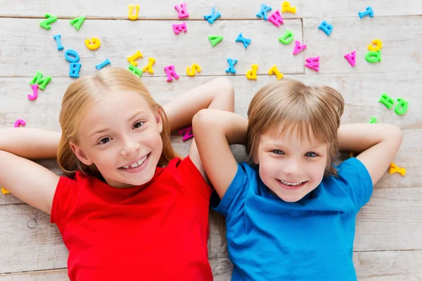 Children lying on the floor with colorful letters — Stock Photo, Image