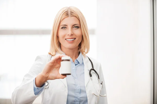 Médico fêmea segurando recipiente com medicamentos — Fotografia de Stock