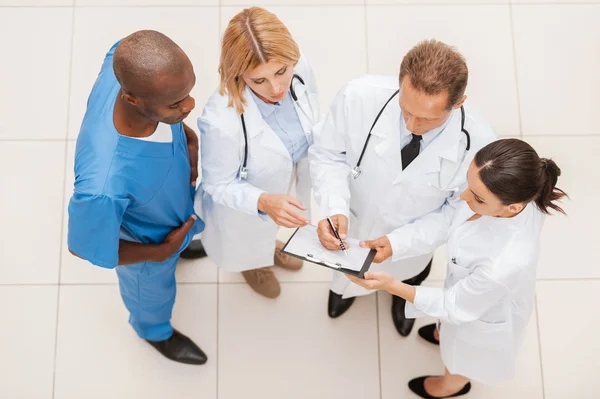 Cuatro doctores confiados discutiendo algo — Foto de Stock