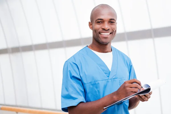 African doctor writing in clipboar — Stock Photo, Image