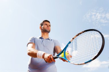 Tenis raket ve top tutan genç adam