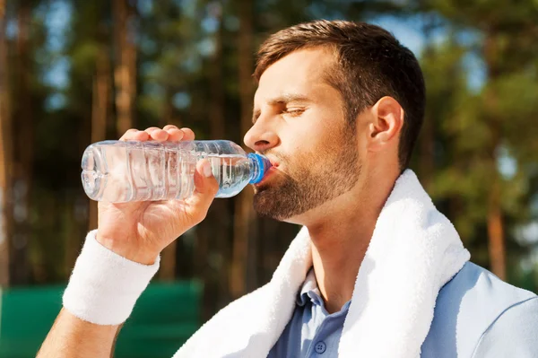 Jovem sedento homem água potável — Fotografia de Stock