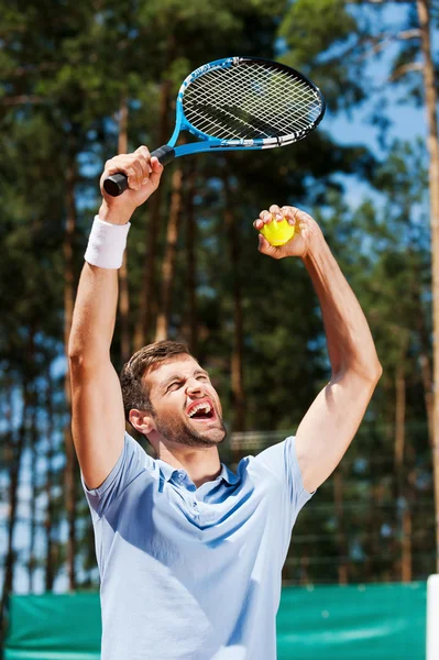 Junger Mann hebt seinen Tennisschläger in die Höhe — Stockfoto