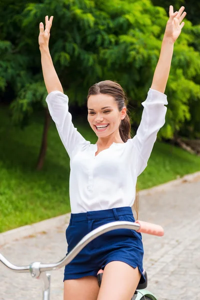 Adoro cavalgar! Jovem feliz andando de bicicleta e mantendo os braços levantados — Fotografia de Stock