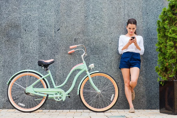 Молодая женщина стоит рядом с велосипедом — стоковое фото