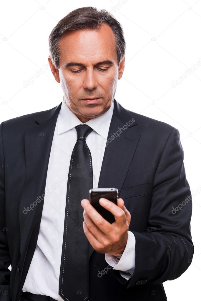 Confident mature businessman holding mobile phone