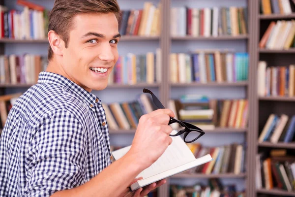 Junger Mann hält Buch und schaut vorbei — Stockfoto