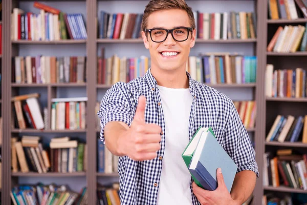 Young man holding books and showing thumb up — Stock Photo, Image
