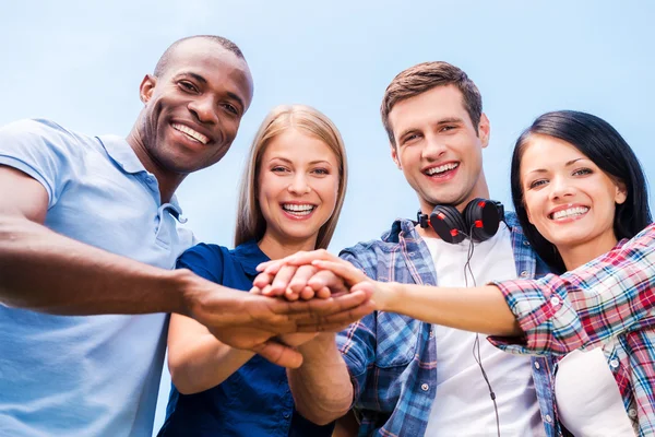 Vier glückliche junge Menschen, die sich kleben und Händchen halten — Stockfoto