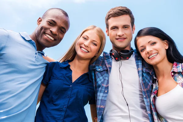 Vier glückliche junge Leute blicken in die Kamera — Stockfoto