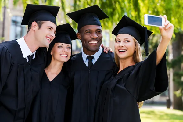 Graduados universitarios en vestidos de graduación — Foto de Stock