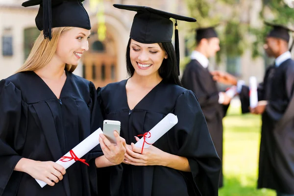Two happy women in graduation gowns — Stock Photo, Image