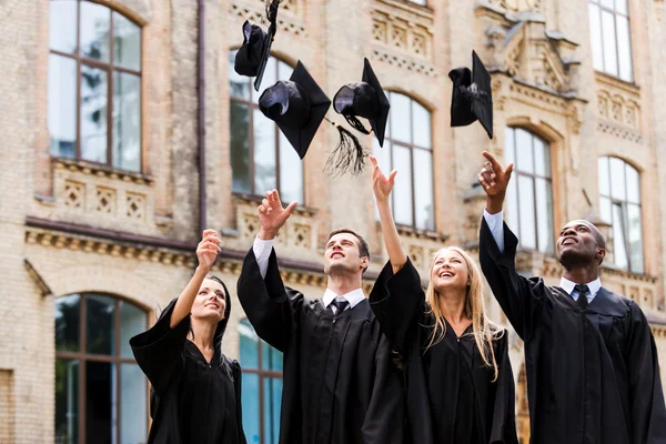 Graduados universitários felizes jogando suas placas de argamassa — Fotografia de Stock
